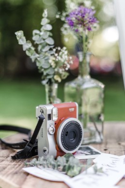 Polaroidkamera auf einem Tisch draußen bei der natürlichen Hochzeit von Olivia und David in Oberbayern