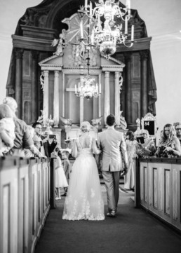 Brautpaar Petra und Daniel beim Einzug in die Kirche zu ihrer Trauung mit Hochzeitsgästen am Hochzeitstag in Schweden fotografiert von Hochzeitsfotograf Veronika Anna Fotografie aus München