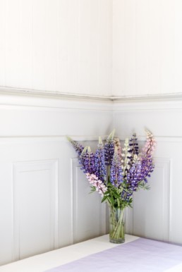 Blumenschmuck in rosa und lila in der Hochzeitslocation am Hochzeitstag von Brautpaar Petra und Daniel in Schweden fotografiert von Hochzeitsfotograf Veronika Anna Fotografie aus München