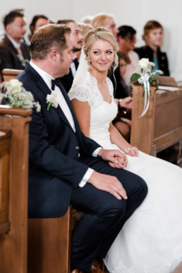Die Braut wirft ihrem Bräutigam in der Kirche verliebte Blicke zu