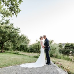 Brautpaat in verliebter Pose am Hofgut Hafnertleiten bei Gartenhochzeit im Sommer